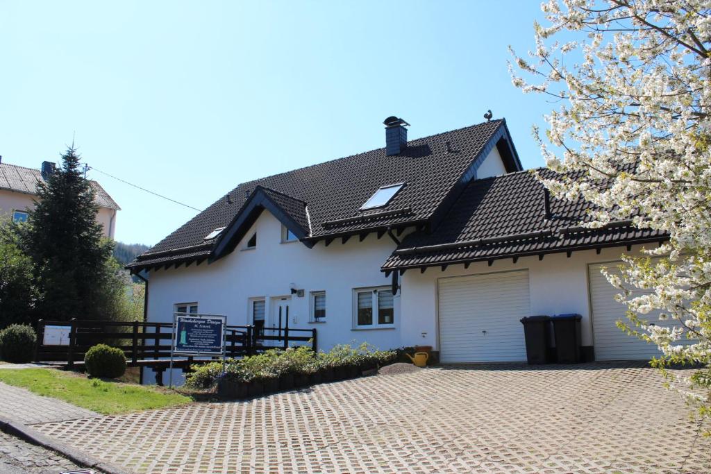 une maison blanche avec un garage dans l'établissement Ferienwohnung am Eifelsteig Vulkaneifel-Auszeit, à Trittscheid