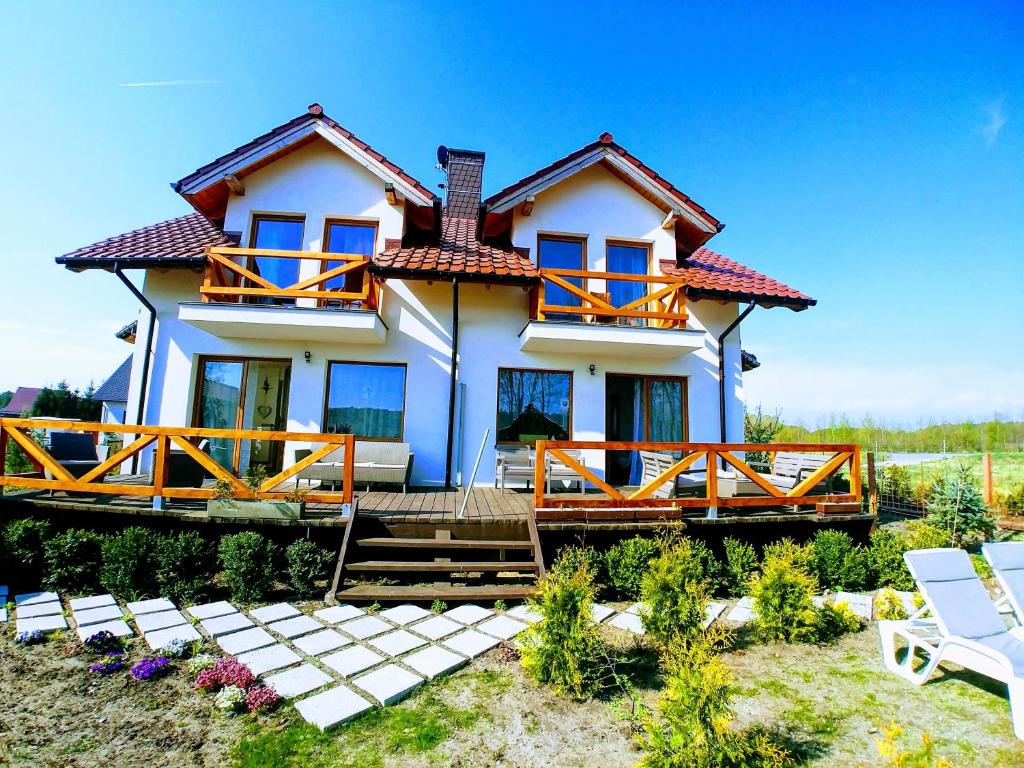 Biały dom z niebieskimi oknami i dwoma krzesłami w obiekcie Rest in Manowo - Holiday Home Baltic Sea w mieście Manowo