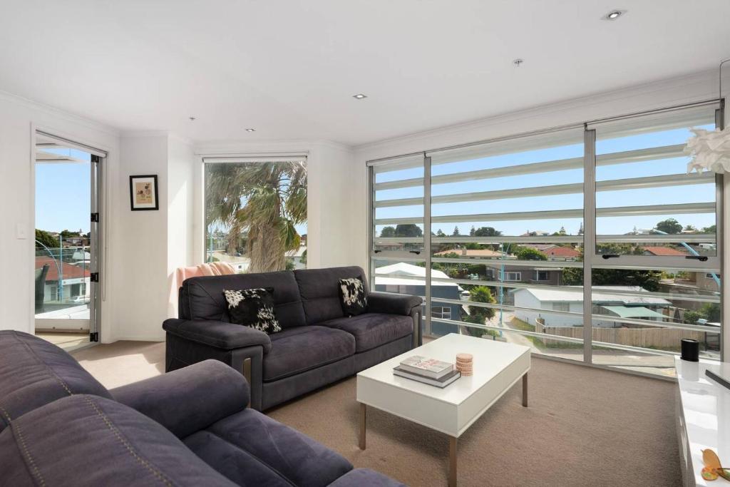 a living room with a couch and a table at Awesome Downtown Location - park the car and walk to everything ! in Mount Maunganui
