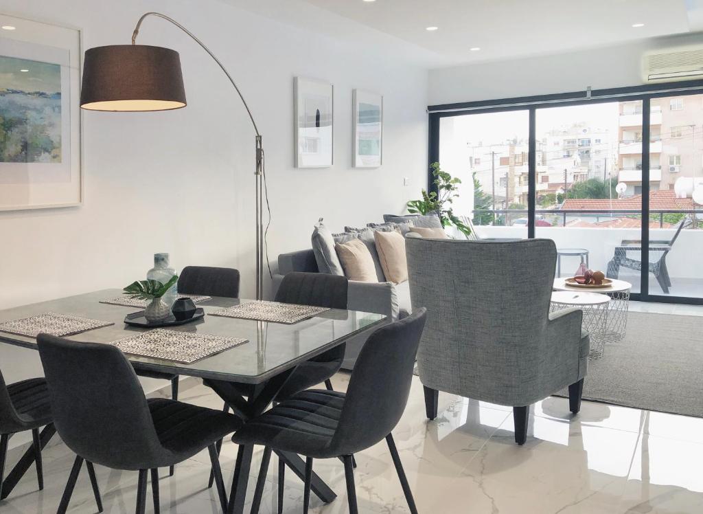 uma sala de jantar com uma mesa de vidro e cadeiras em Metro Court Apartments em Limassol