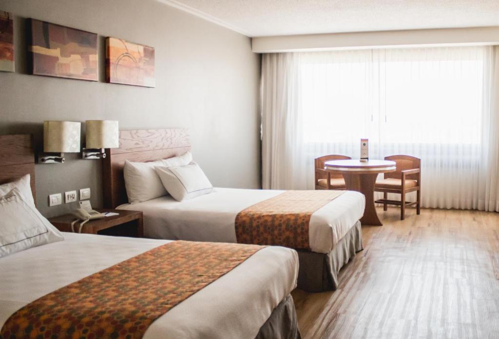 Cette chambre comprend 2 lits et une table. dans l'établissement Hotel Mirage, à Querétaro