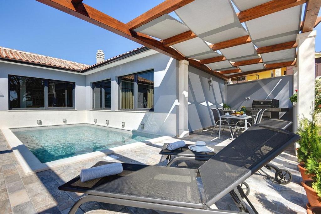un patio con piscina, mesa y sillas en Villa Sunny Home, en Vodnjan