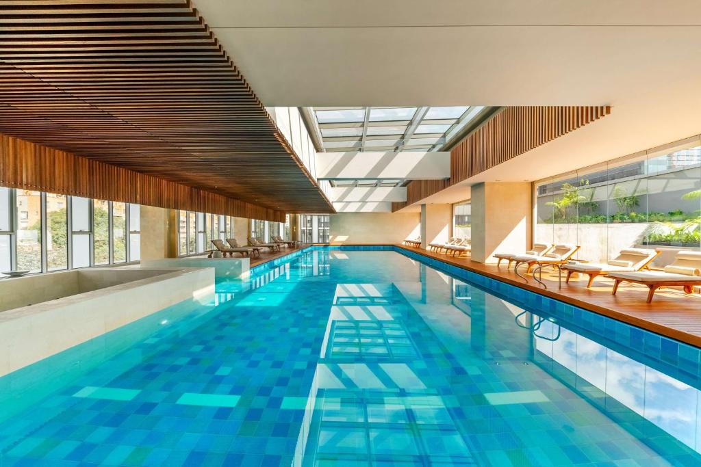 - une piscine avec des chaises et des tables dans un bâtiment dans l'établissement Grand Hyatt Bogota, à Bogotá