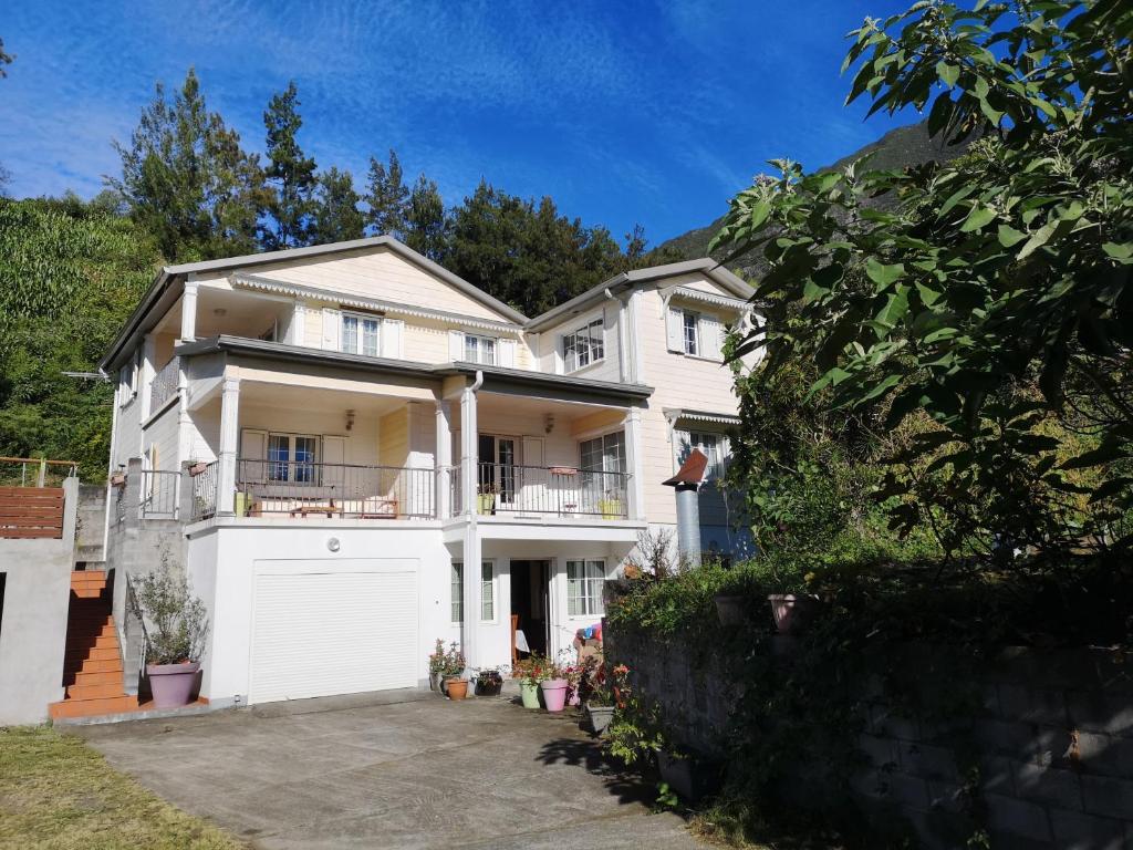 une grande maison blanche avec un garage blanc dans l'établissement Le papangue, à Salazie