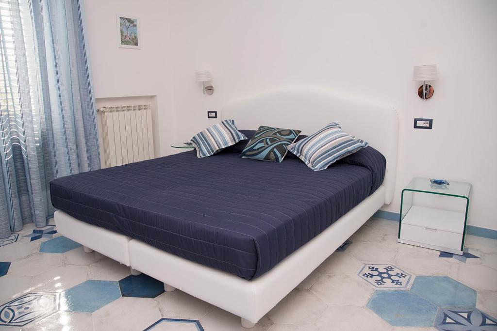 La Gemma di Ravello في رافيلو: غرفة نوم بسرير كبير عليها شراشف ووسائد زرقاء