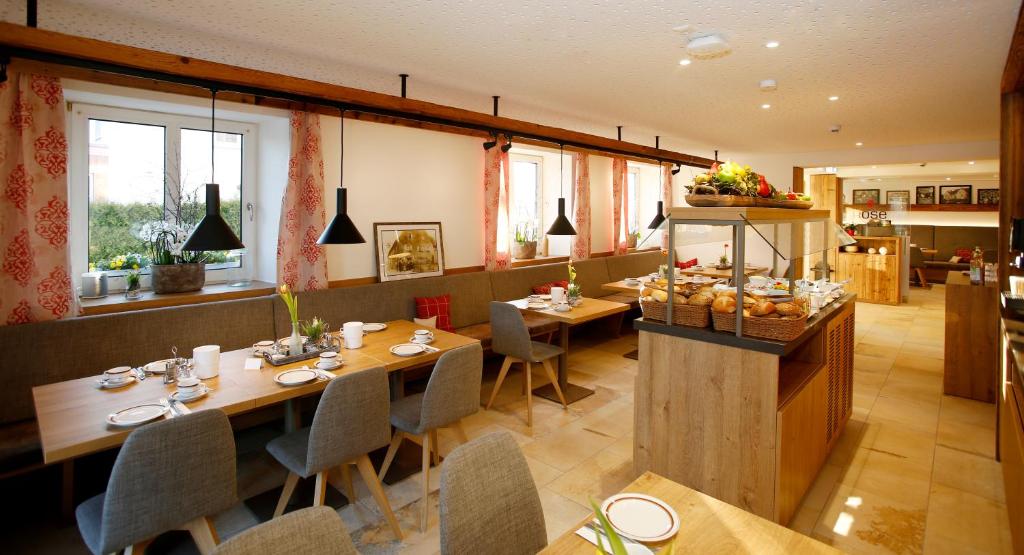um restaurante com mesas e cadeiras de madeira e janelas em ApartHotel Rose em Ellwangen