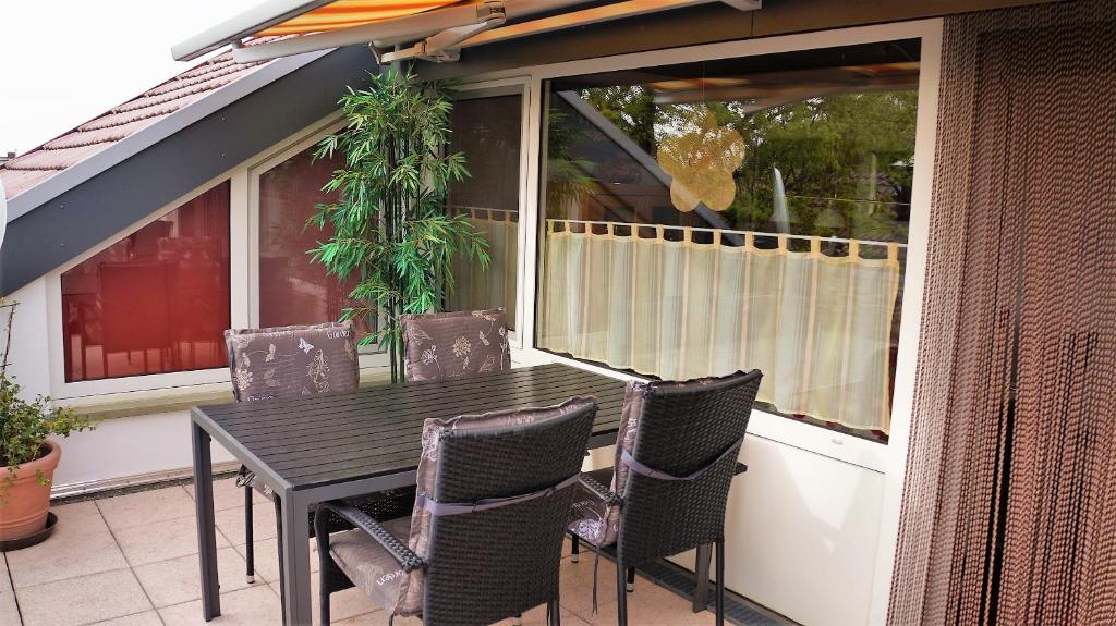 einen Tisch und Stühle auf einer Terrasse mit einem Fenster in der Unterkunft BodenSEE Apartment Langenargen Möwenweg in Langenargen