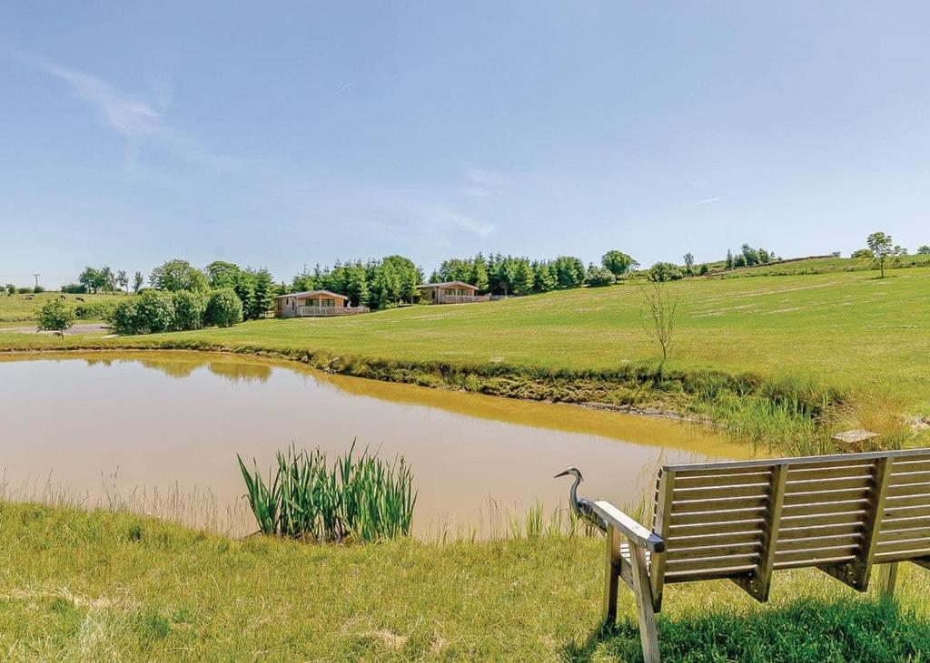 a park bench sitting in front of a pond at Hazelhurst Lodges in Ashover