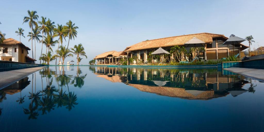 a resort swimming pool with palm trees and buildings at Wattura Resort & Spa in Negombo