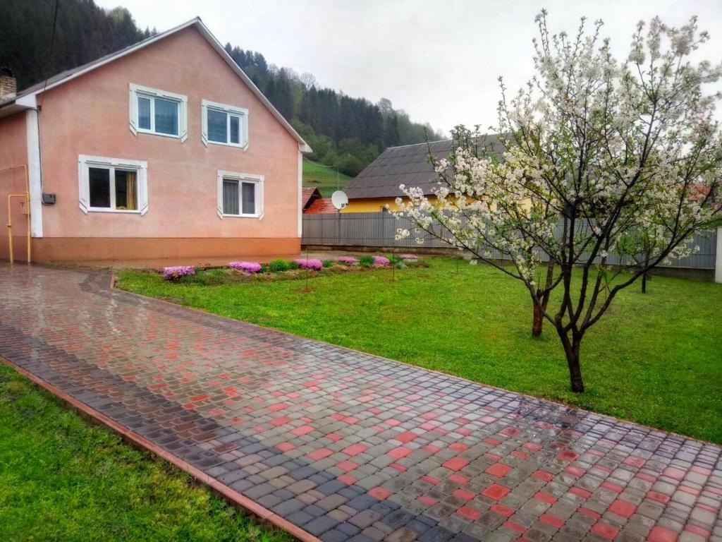 a house with a tree and a brick driveway at Відпочинок у Карпатах in Volovets