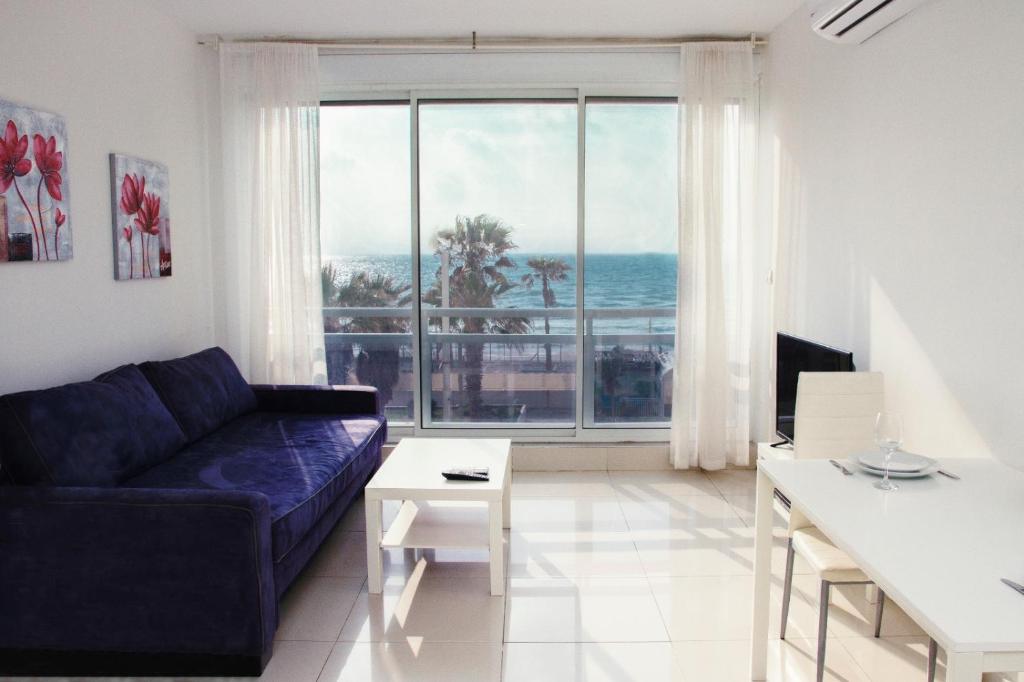 a living room with a blue couch and a view of the ocean at Apartment Beauty in Bat Yam