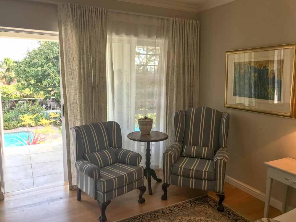 2 Stühle und ein Tisch im Wohnzimmer mit Fenster in der Unterkunft Lavender Suite in Kapstadt