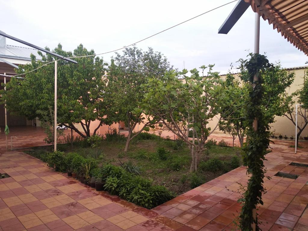 un jardín con árboles y plantas en una acera en YOKUB Guest House, en Samarkand