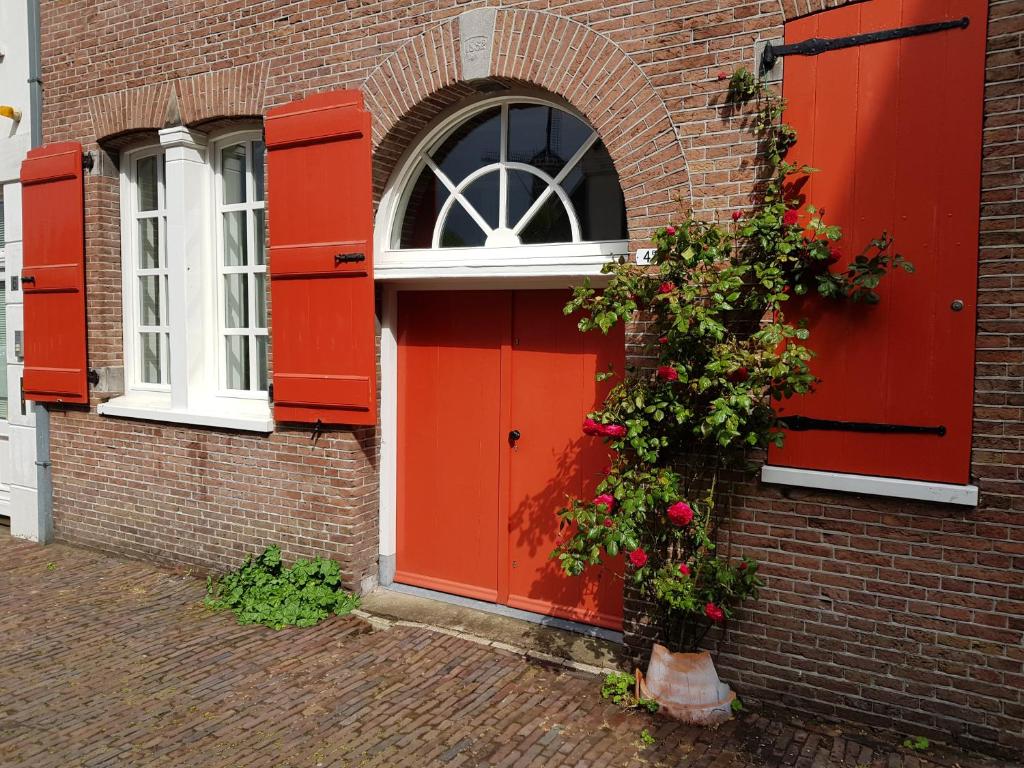 una porta rossa su un edificio di mattoni con fiori di Het Pakhuis Schiedam a Schiedam