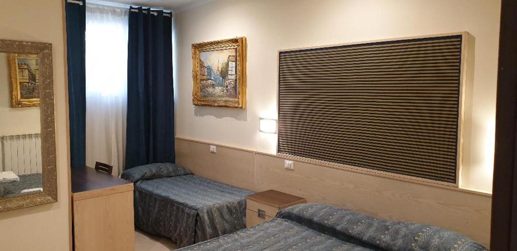 a hotel room with two beds and a mirror at Hotel Chopin in Fiumicino