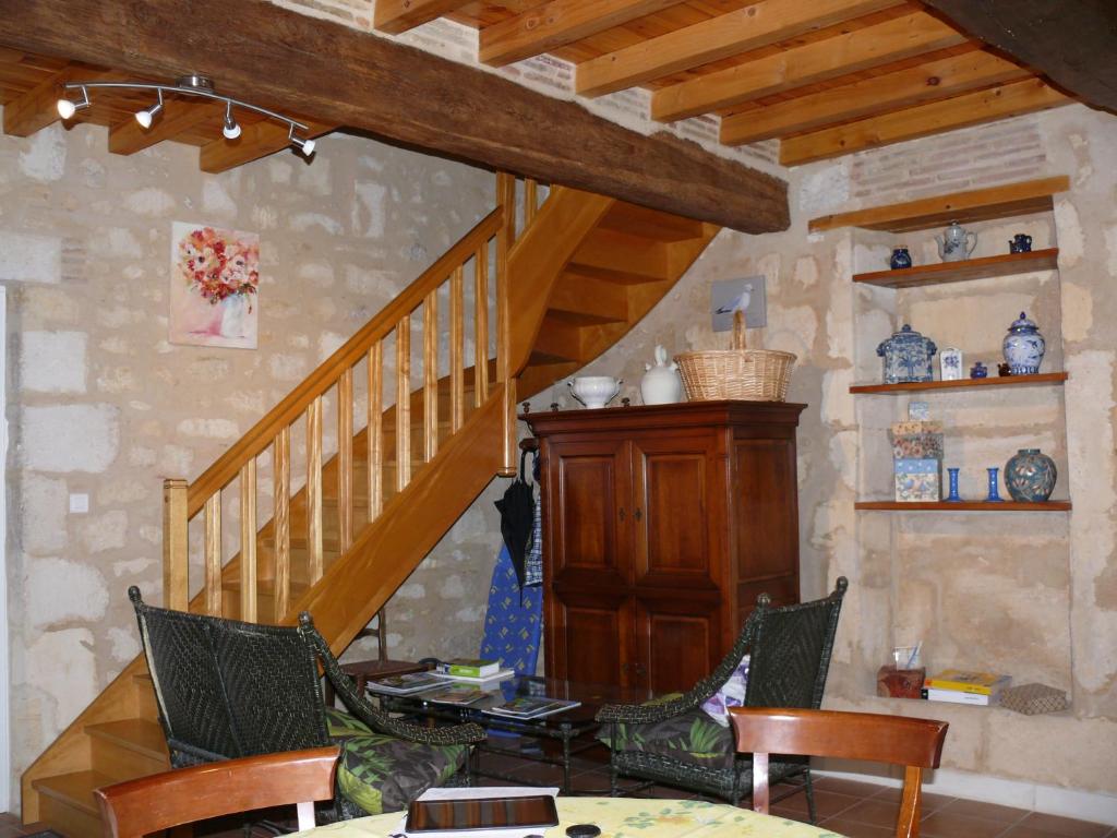 una sala de estar con una escalera de madera y sillas en Les Oiseaux en Saint-Émilion