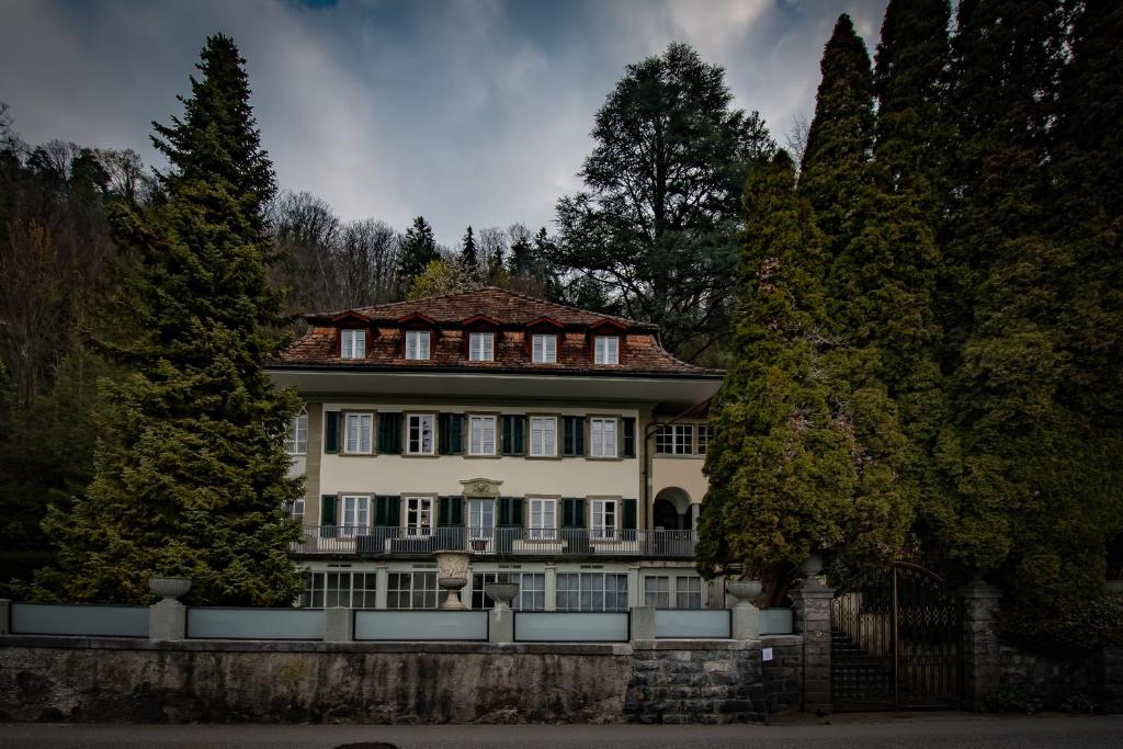 una grande casa con una recinzione di fronte agli alberi di Villa Pochon a Gunten