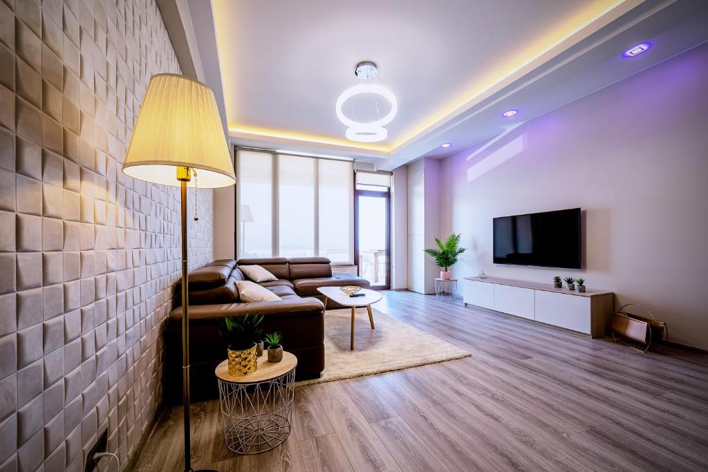 uma sala de estar com um sofá e uma televisão em Penthouse Chic by Landev em Braşov