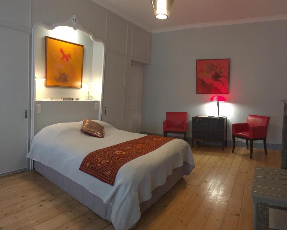 a bedroom with a bed and two red chairs at LES CHAMBRES D'HOTES DU PALAIS in Douai