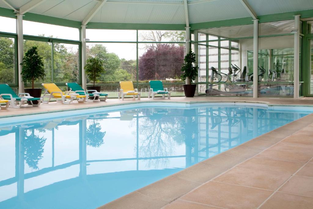 a large swimming pool with chairs and tables at Domaine des Roches Hotel & Spa in Briare