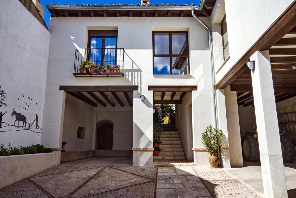 a white house with a balcony with flowers on it at Casa del Hortelano in Chinchón