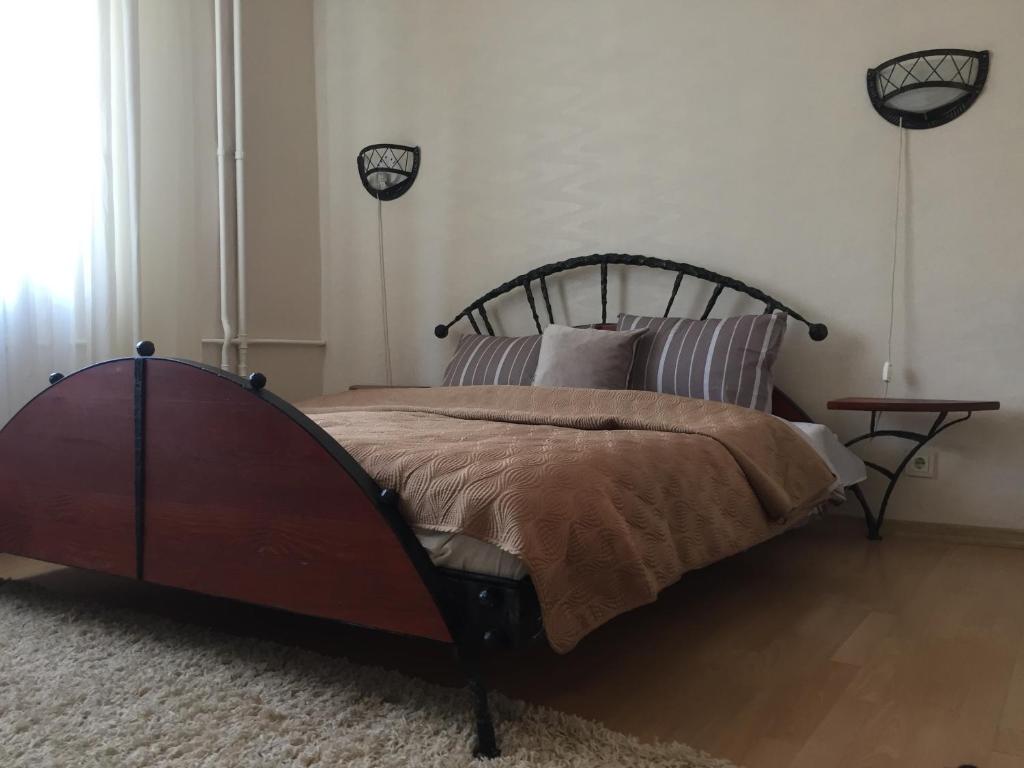 a bedroom with a bed with a wooden headboard and a table at Old Town apartament in Šiauliai