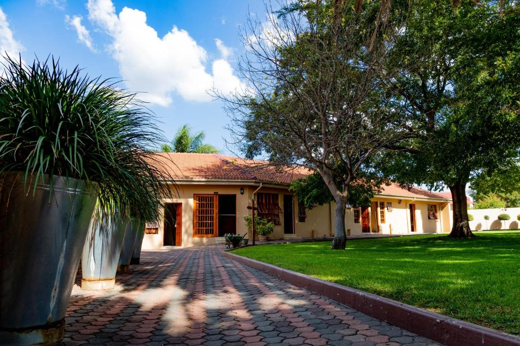 a house with a brick driveway in front of a yard at Tambati Overnight and Conference Center in Polokwane