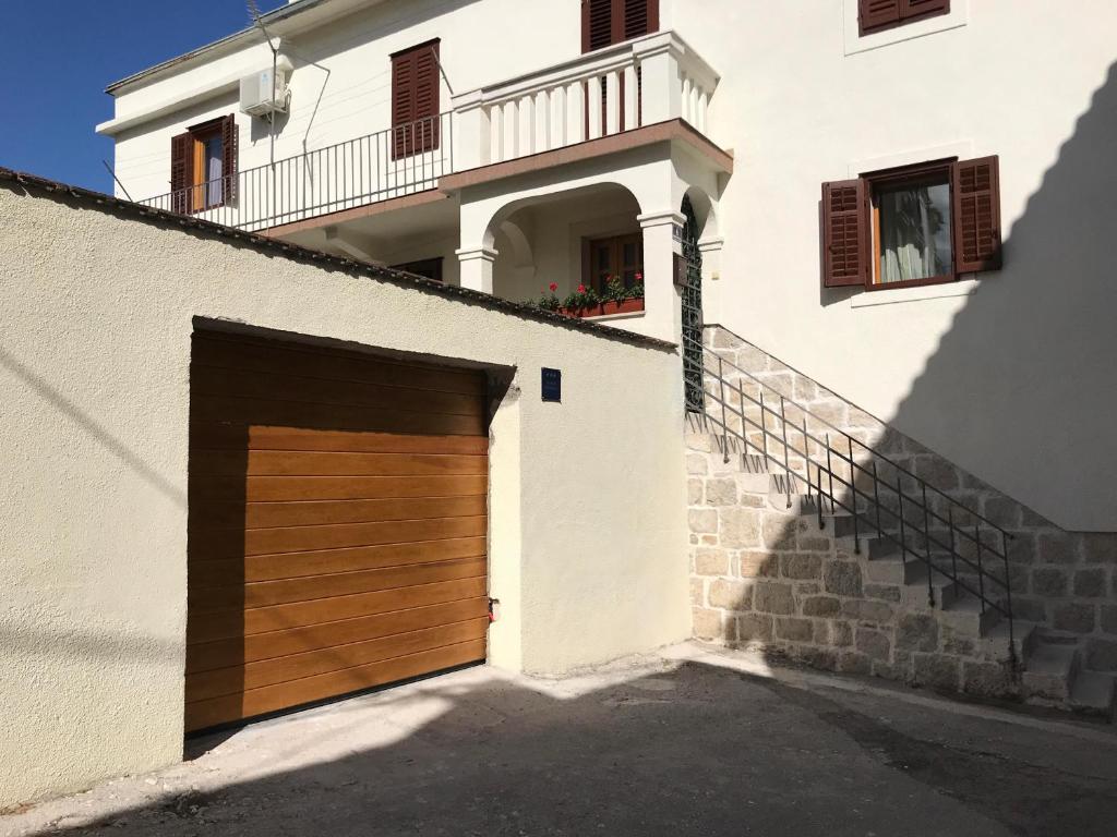 un edificio bianco con una porta in legno per il garage di Studio Apartment Sabljic a Kaštela (Castelli)