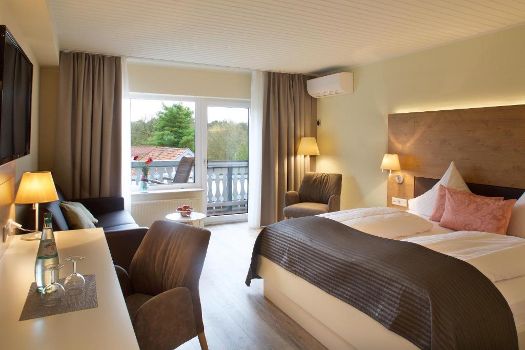 a hotel room with a bed and a desk and a window at Jammertal Resort in Datteln