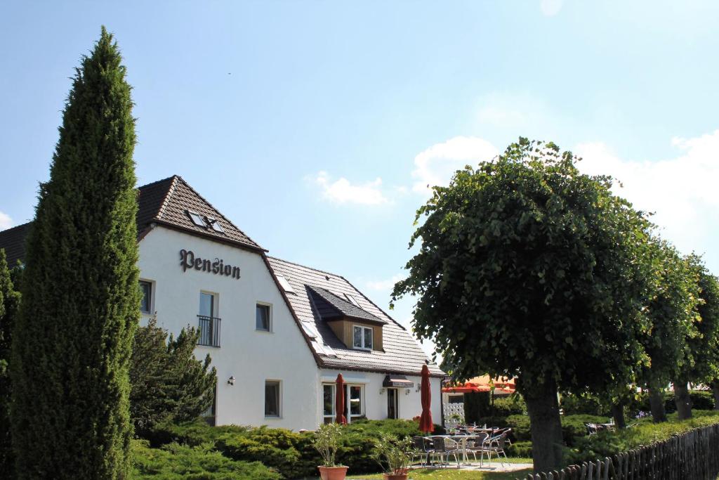 un edificio bianco con un albero di fronte di Pension Jägerrast a Boek