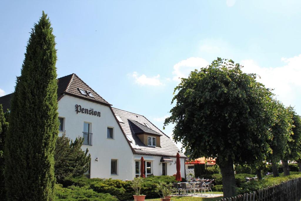 a white building with a tree in front of it at Pension Jägerrast in Boek