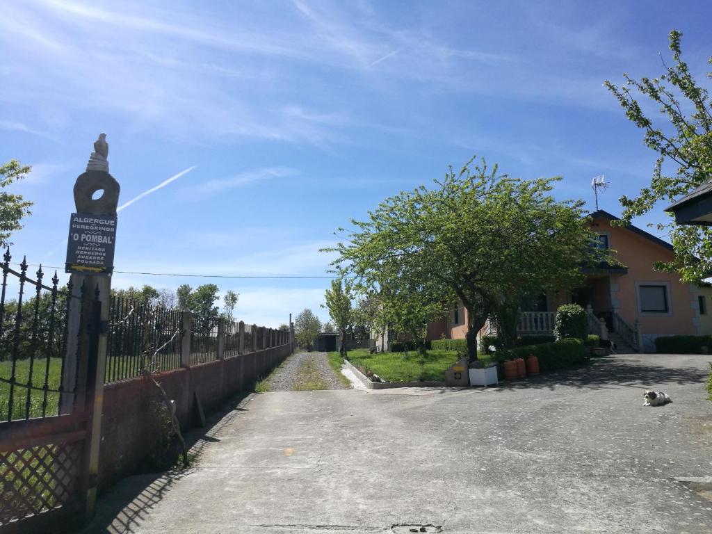 een straat met een hek en een klok op een paal bij Albergue O Pombal in Sarria