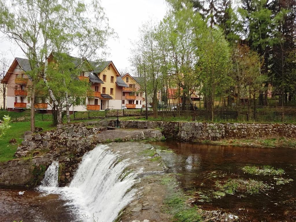 カルパチにあるApartamenty Rezydencja Parkowa Sun&Fun -blisko centrumの家屋が並ぶ川前の滝