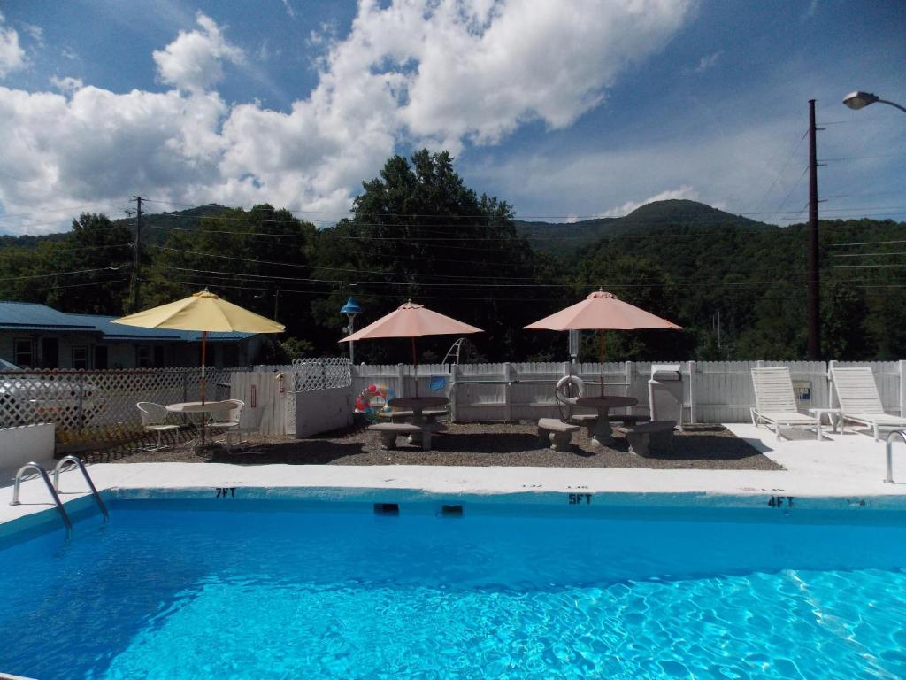 马吉谷Clarketon Motel - Maggie Valley的一个带遮阳伞和桌椅的游泳池