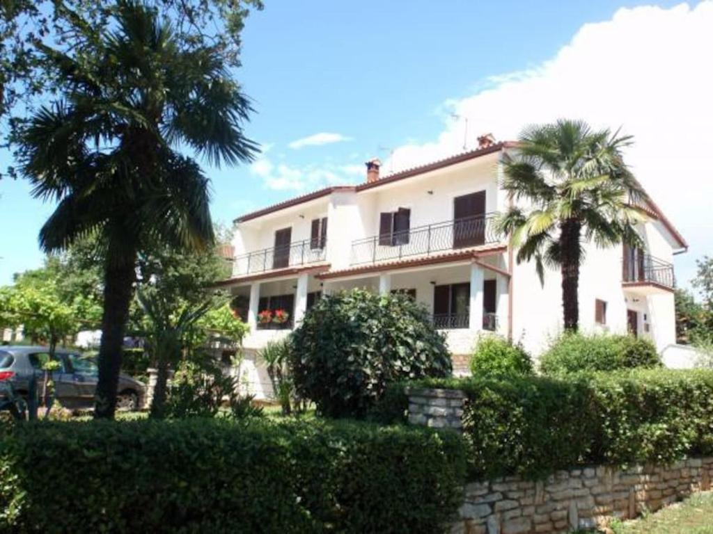 a white house with palm trees in front of it at Apartments Nina, Pinta & Santa Maria in Nova Vas