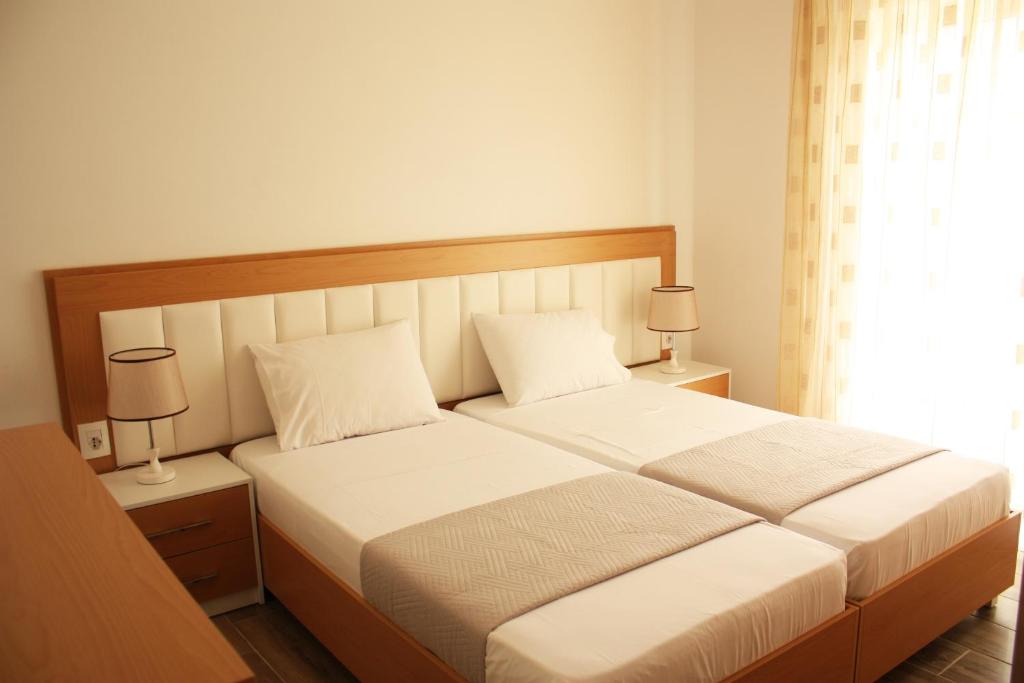 een slaapkamer met een bed met 2 lampen en een raam bij Alexandra´s Apartments in Sarandë
