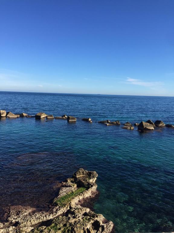 a large body of water with rocks in it at The Ronco Apartment in Siracusa