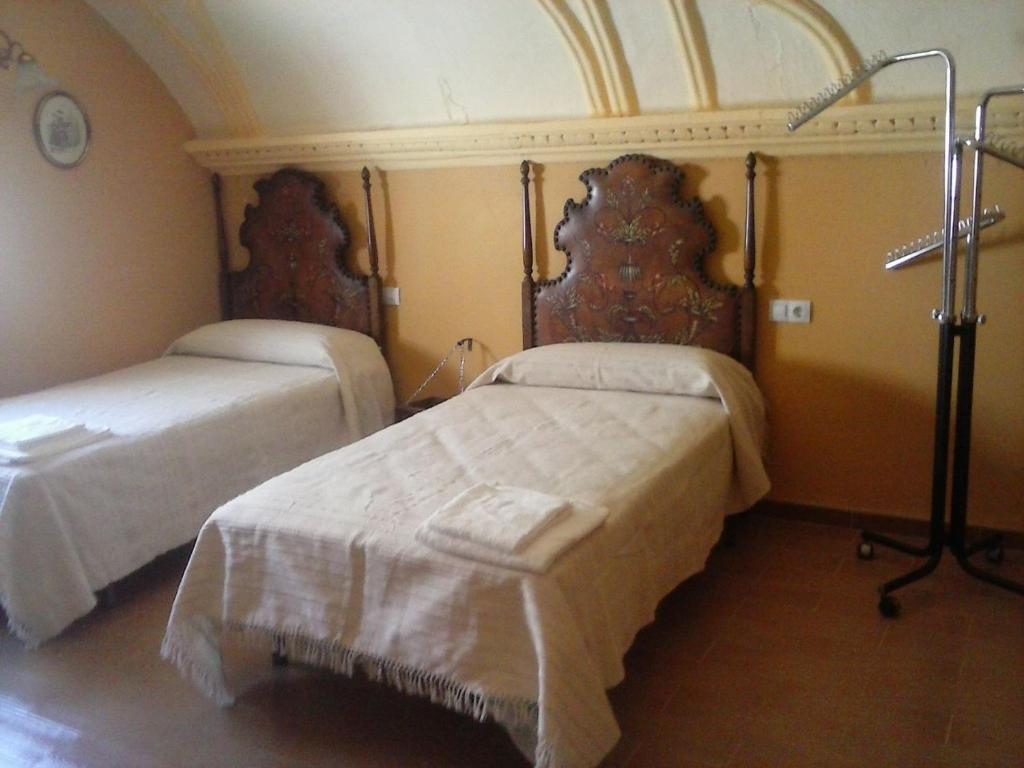 a bedroom with two beds with white sheets at Casa Rural Antigua Ermita del Rosario in Teba