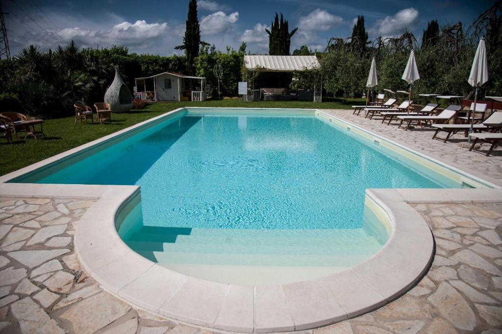 a swimming pool with blue water in a yard at Cevoli Country Resort in Lari