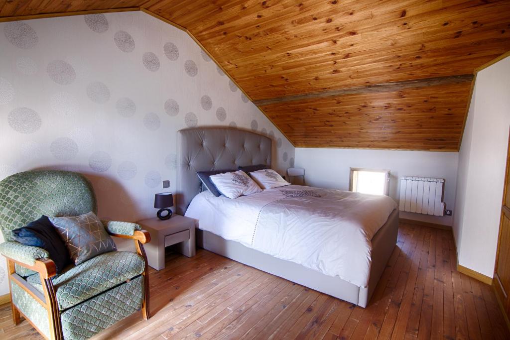 a bedroom with a bed and a chair at Chambre d'hôtes Au Chant des Vents in Thurageau