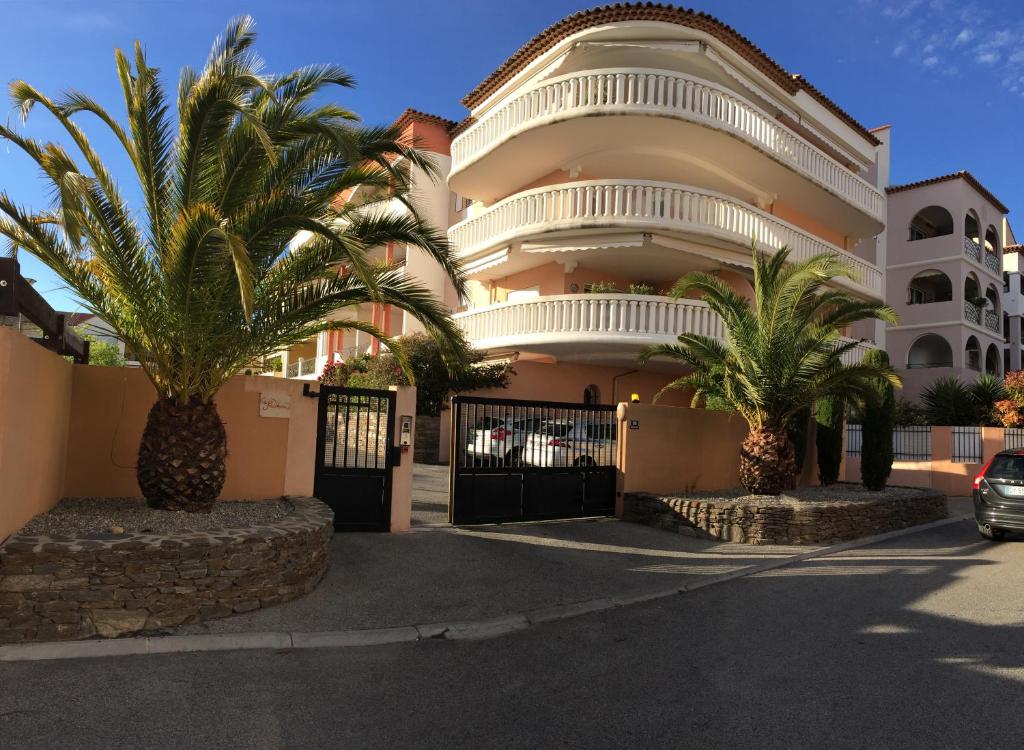 un bâtiment avec des palmiers en face de celui-ci dans l'établissement Le Palais Vénitien, à Saint-Cyr-sur-Mer