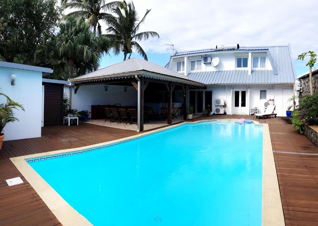 una gran piscina azul frente a una casa en La Maison des Hôtes en Saint-Joseph