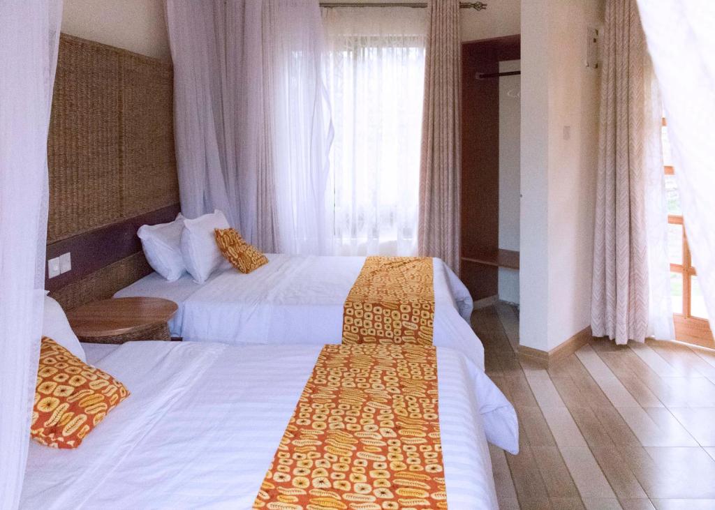 a hotel room with two beds and a window at Tooro Fairway Hotel in Fort Portal
