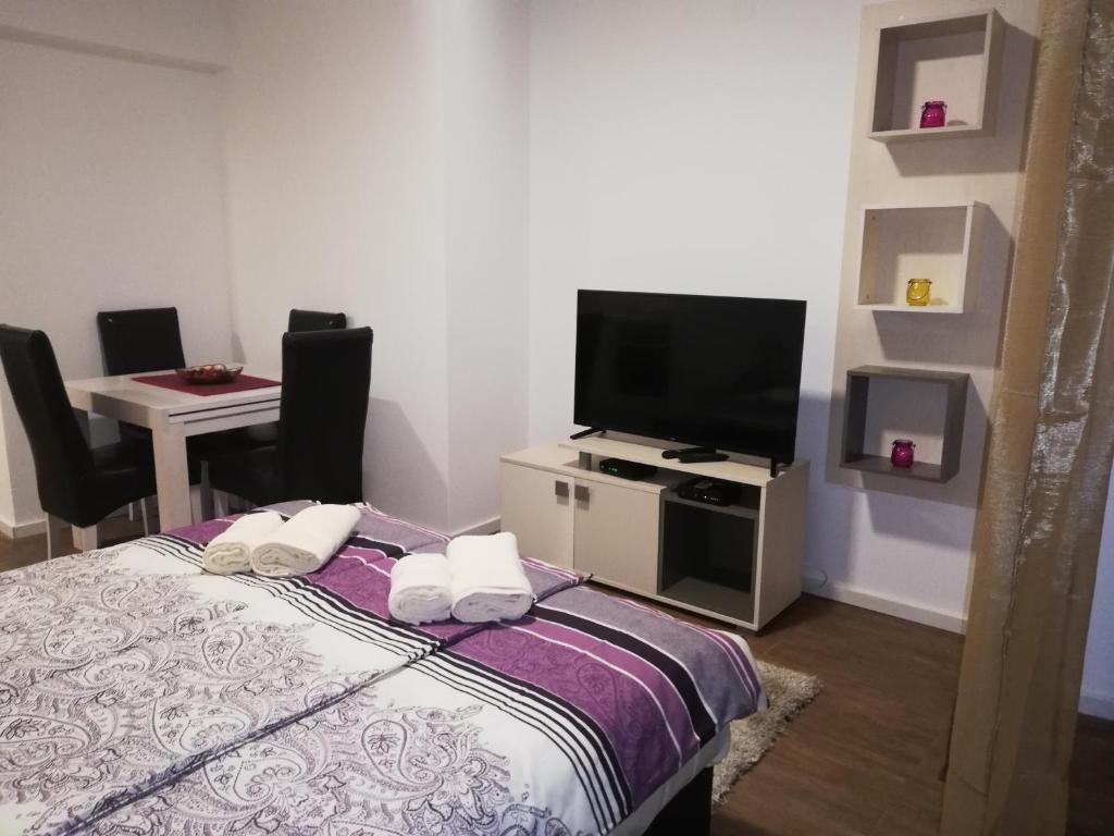 Schlafzimmer mit einem Bett und einem Flachbild-TV in der Unterkunft Laguna apartman 2 in Niš