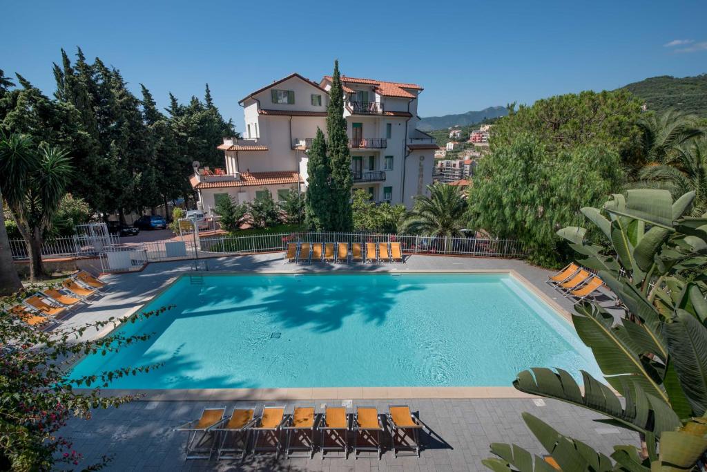 a swimming pool with chairs and a building at Residence Oleandro in Pietra Ligure