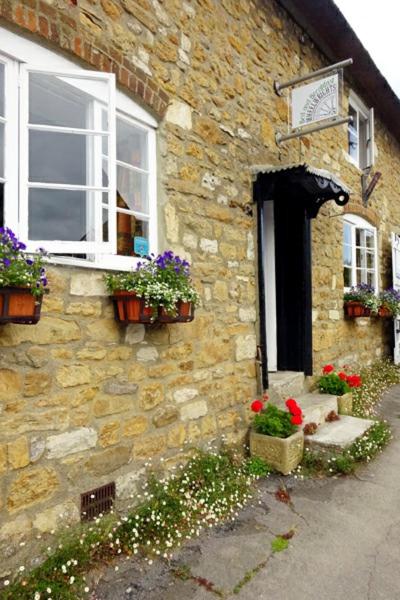 a stone house with flowers in front of it at Wheelwrights in Abbotsbury