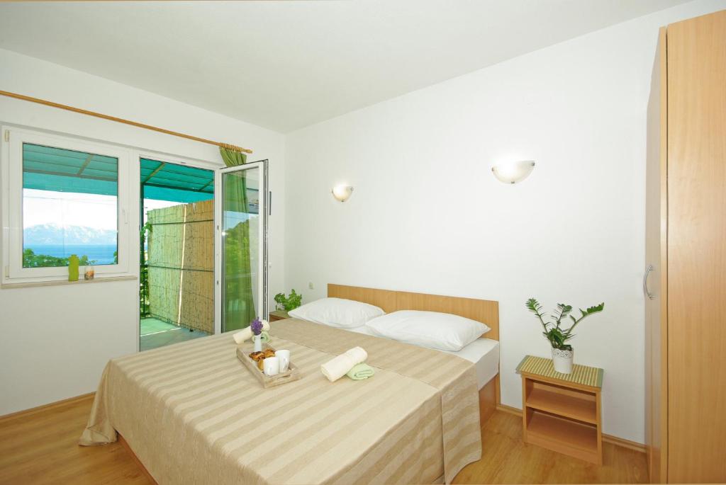 une chambre blanche avec un lit et une fenêtre dans l'établissement Apartmani Maslina, à Gradac
