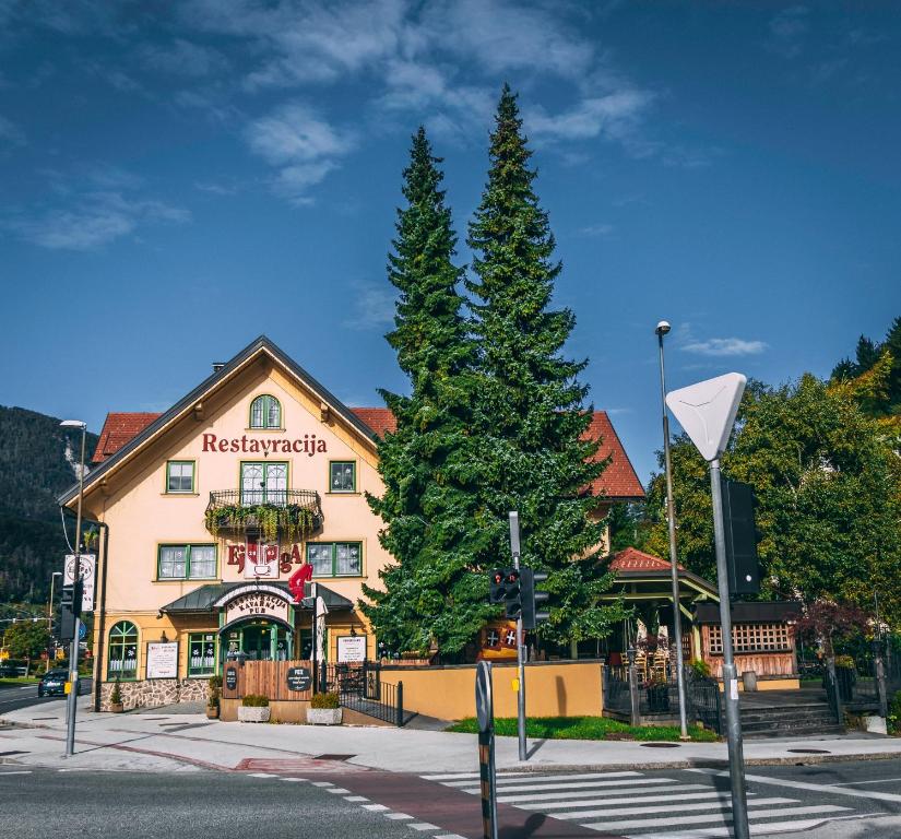 a large building with a tree in front of it at Guest House EJGA in Jesenice