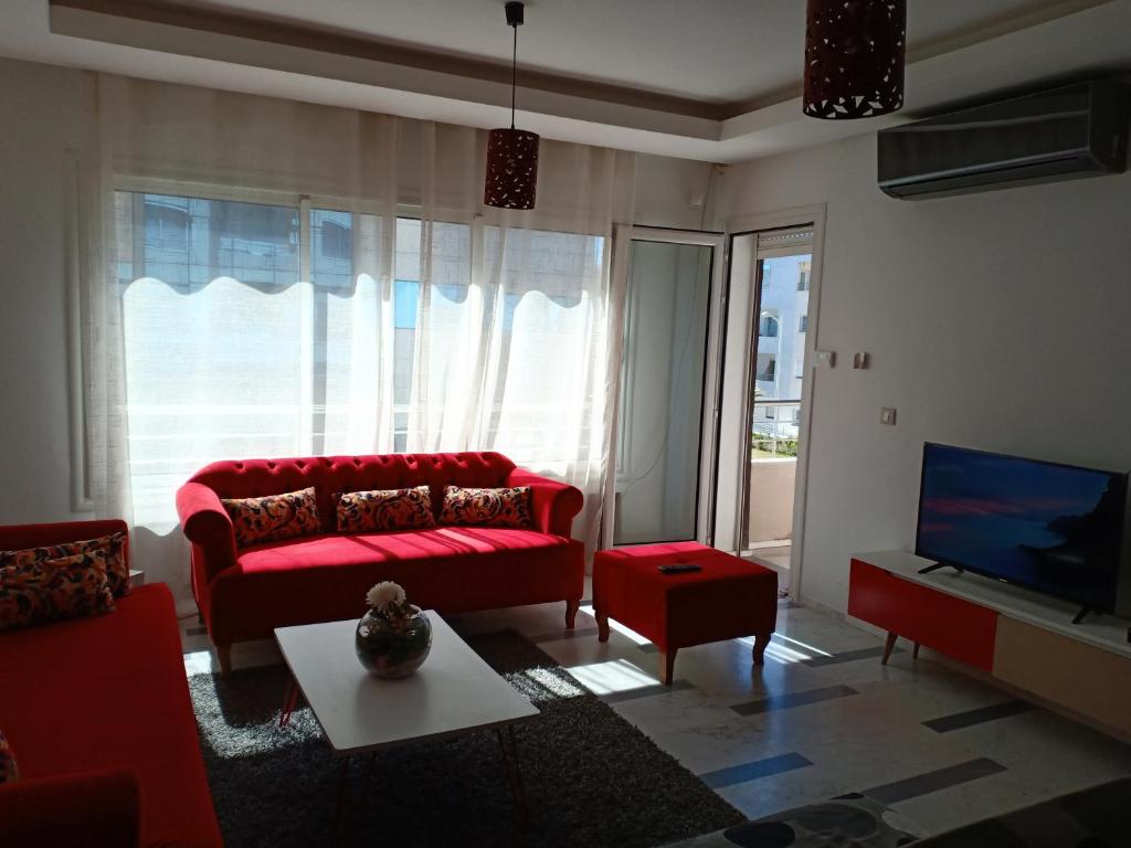 a living room with a red couch and a tv at Harmony Appartement 13 in Tunis