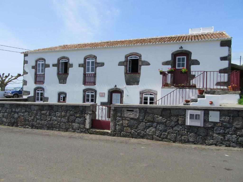 a white building with windows and a stone wall at O Antigo Lagar in Cinco Ribeiras